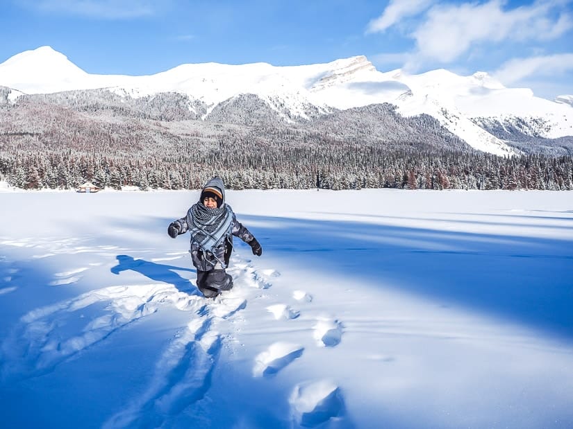 A boy walking in deep snow at Maligne lake in winter