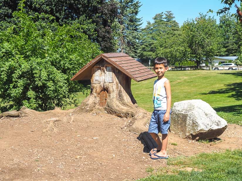 A kid standing beside a little gnome house in Mill Lake Park, one of the best parks in Abbotsford for kids