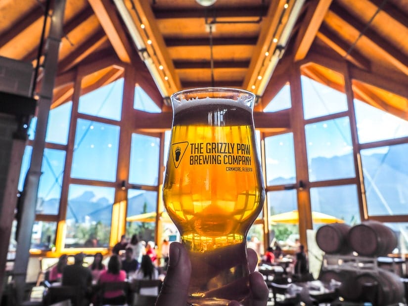 Glass of beer held up inside Tank310, one of three breweries in Canmore