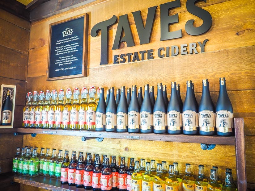 Shelf of bottles of cider and a Taves Family Cidery Sign at Taves Family Apple Barn