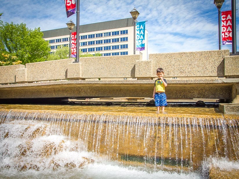 A boy playing in a water fountain at the Legislature Grounds in Edmonton