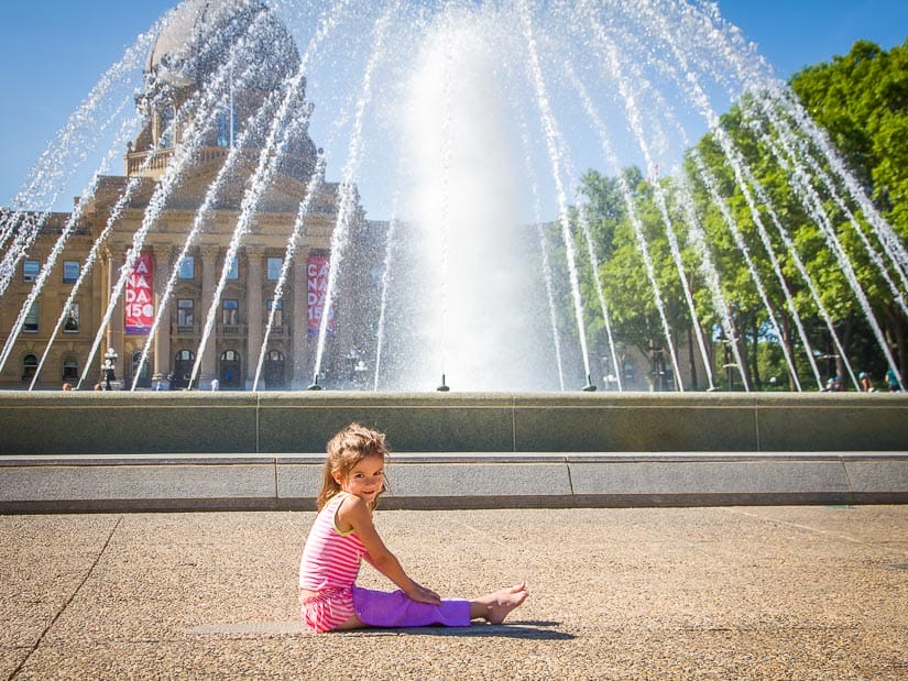 A girl in front of a large fountain at Alberta Legislature Grounds
