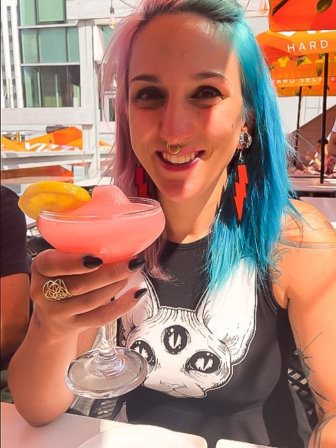 A woman with colorful hair having a cocktail on the patio at Central Social Hall in Edmonton