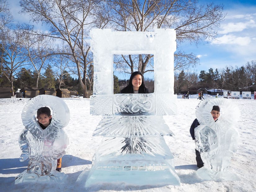 A mother and two kids posing with some ice sculptures at Silver Skate Festival in Edmonton
