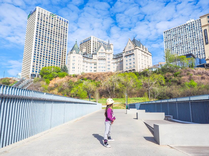A kid standing on Edmonton Funicular Promenade, with buidings of downtown in the background