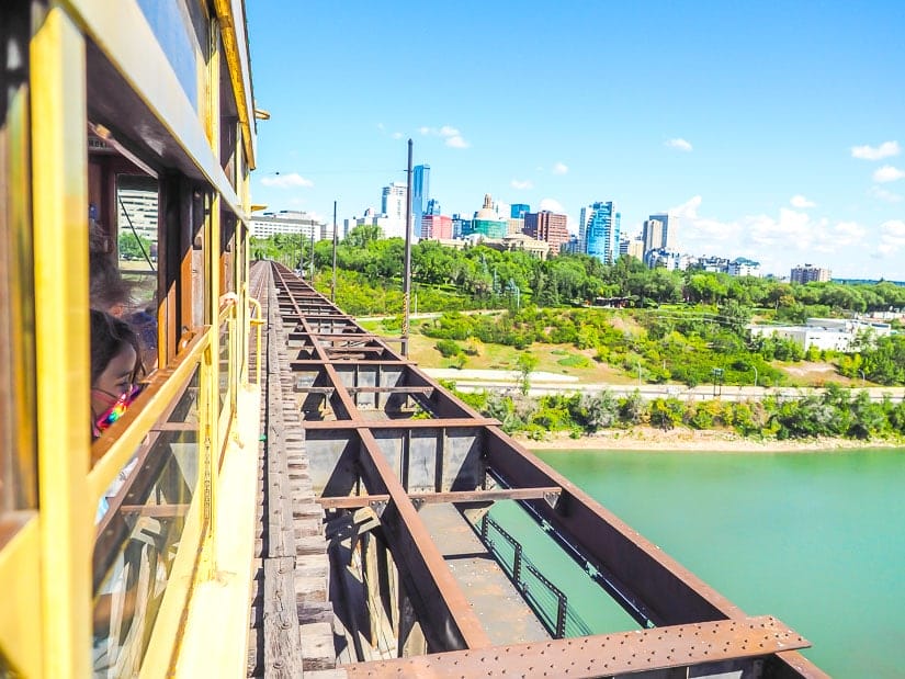 A girl looking out the window of the High Level Bridge Streetcar, with downtown Edmonton in the background