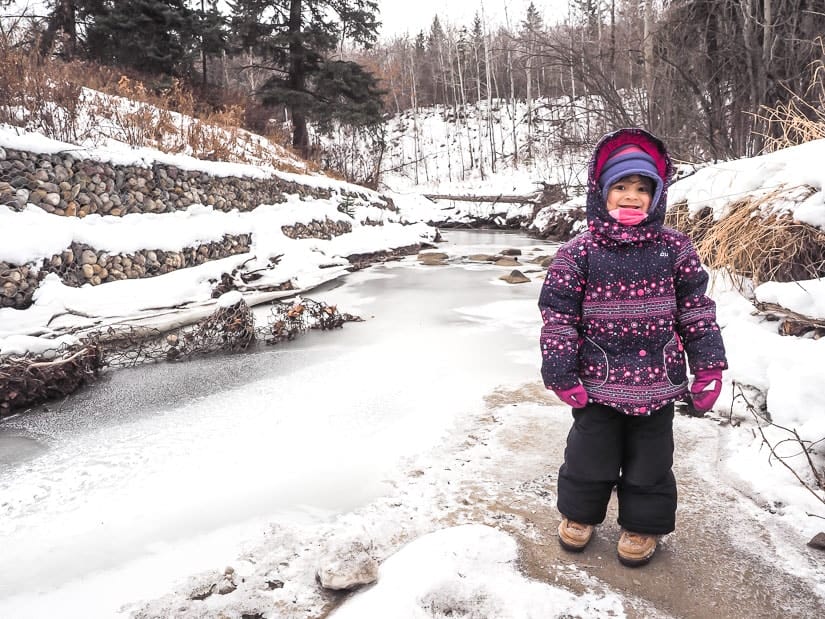 A girl standing beside a frozen creek in Mill Creek Ravine
