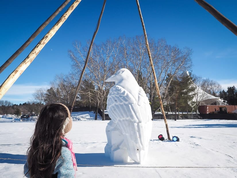 A girl looking at an ice sculpture of a bird at Edmonton Silver Skate Festival