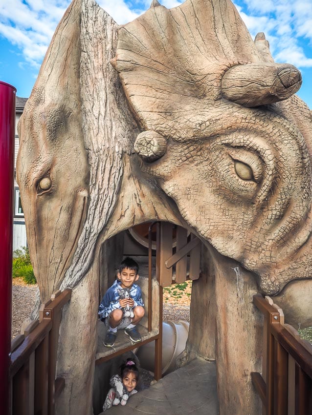 A kid playing in a dinosaur themed playground in Leduc