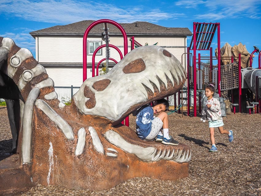 Two kids playing in a dinosaur-themed park in Leduc, Alberta