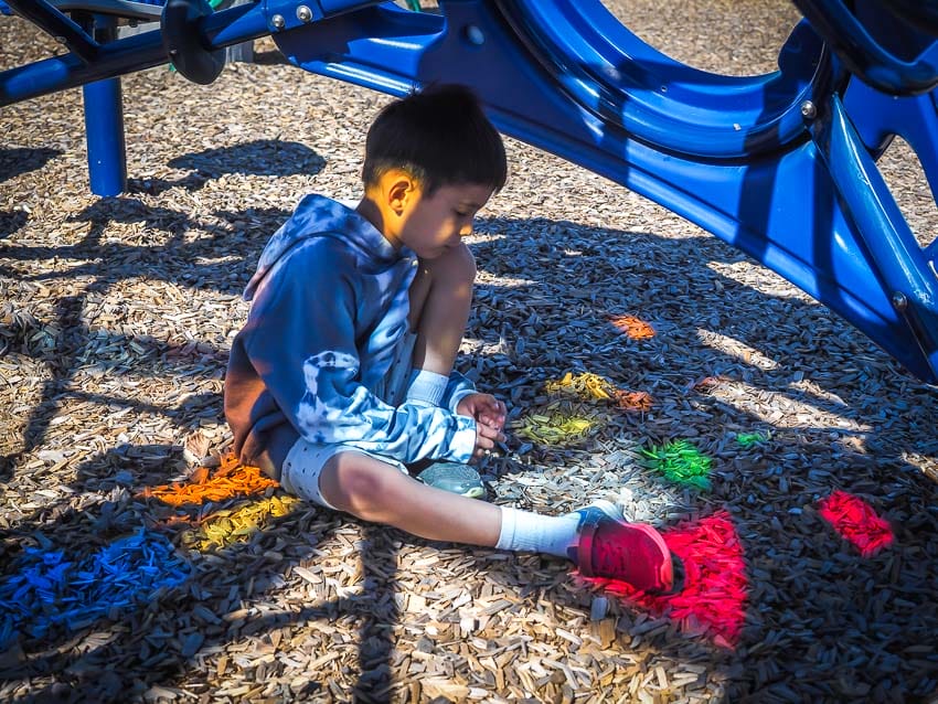 A kid with colorful lights shining on him in Svend Hansen playground, Edmonton