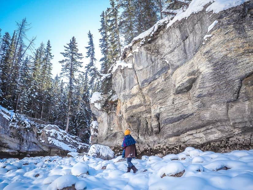 A woman walking in a wide section of frozen Maligne Canyon