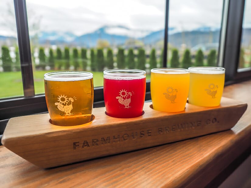 A flight of beers on a window sill, with mountains and trees visible out the window