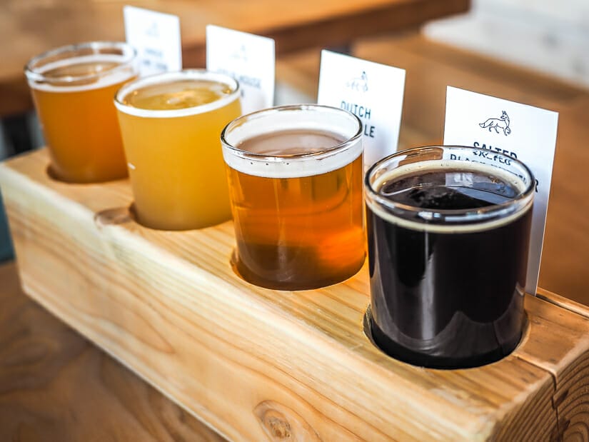 A flight of four glasses of beer in a wooden holder at Fieldhouse brewing