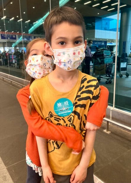 A boy and girl with masks and quarantine sticker outside of Taiwan's main airport