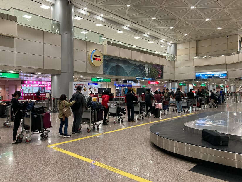Line of people in the baggage collection area of Taoyuan Airport during Covid