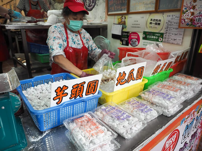 A woman making taro balls with several types on display in Shenkeng