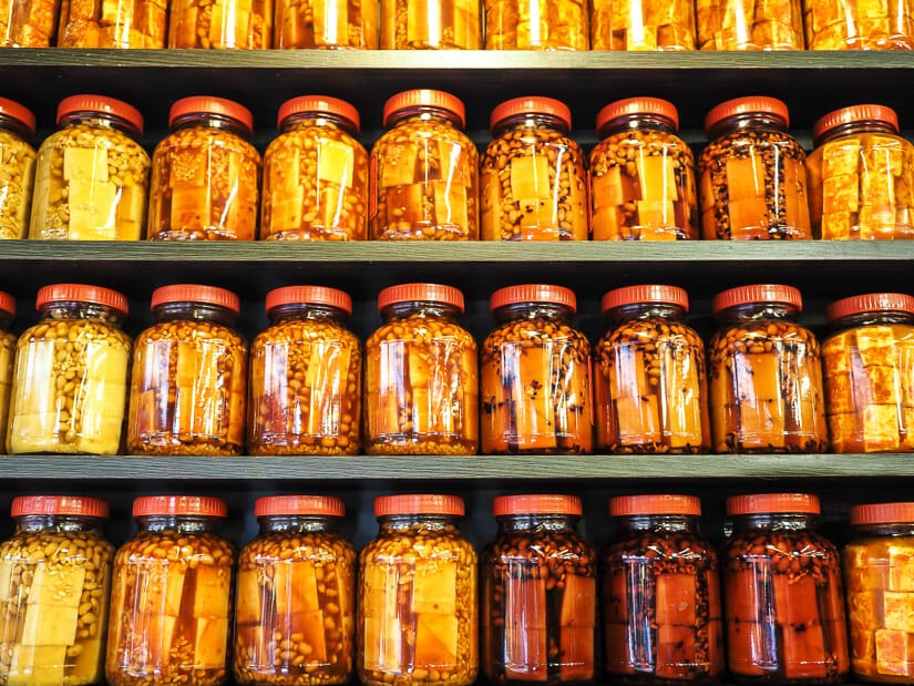 Some shelves with rows of jars containing fermented tofu cubes for sale in Shenkeng Old Street