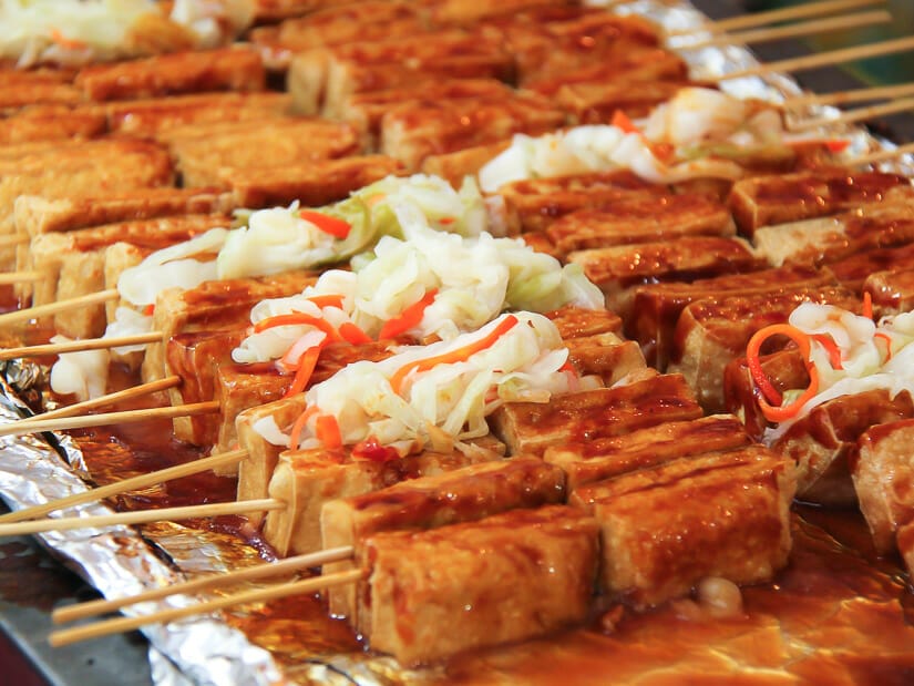 A tray filled with slabs of stinky tofu with sticks sticking out of them shot in Shenkeng, Taiwan's stinky tofu village