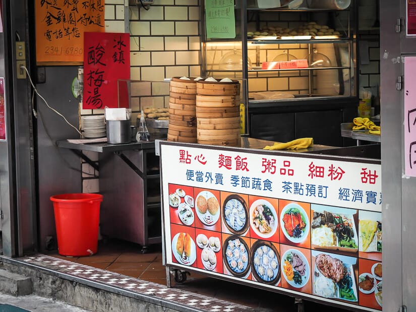A food stall with its menu of dishes posted on the front and baskets for steaming food on top, at Jin Jin Yuan restaurant on Yong Kang Street