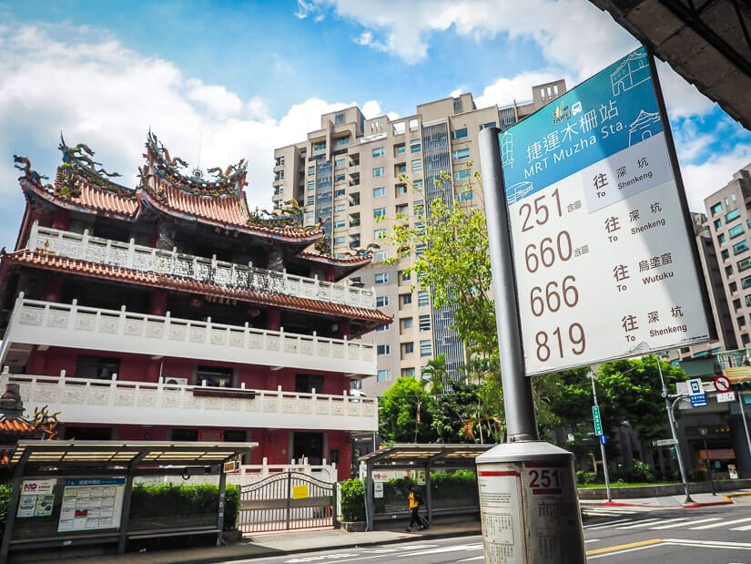 A sign showing the buses that go to Shenkeng from Mazha MRT, with a temple across the street