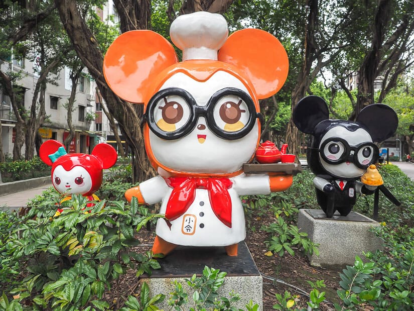 Three cute statues of cartoon characters standing among trees in Yongkang Park