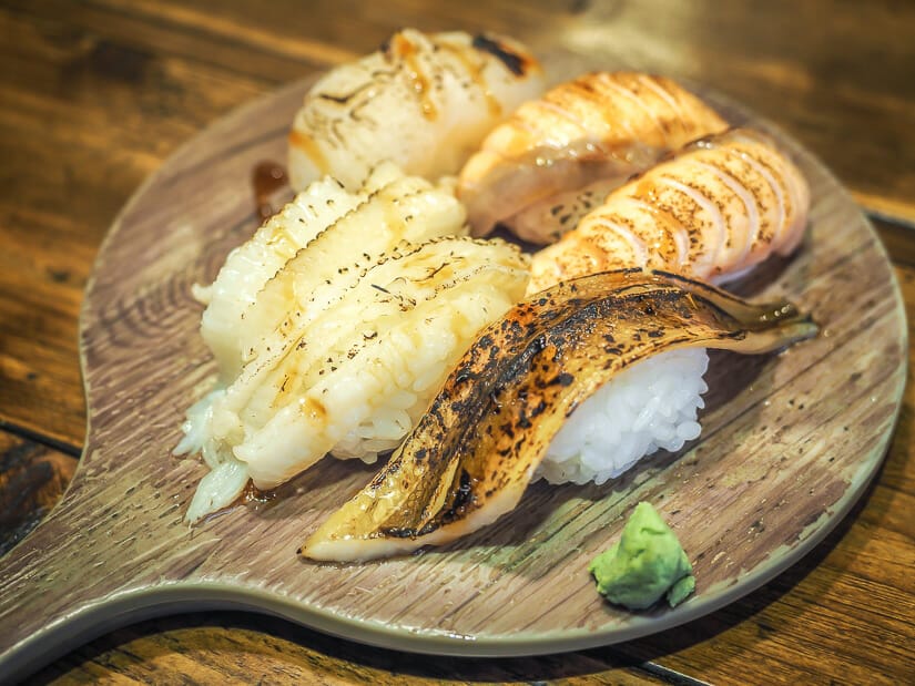 A round wooden plate with six pieces of sushi on it shot in a traditional market in Tainan