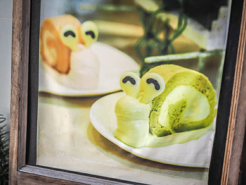 A cafe sign with a picture of two cakes that are shaped like snails