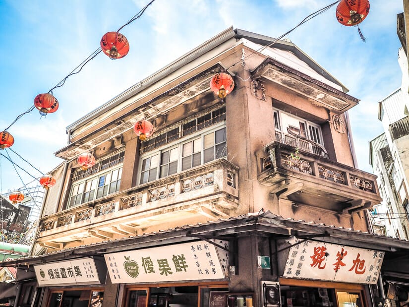 Exterior of an old, famous building in Tainan with shops at bottom and red lanterns hanging in the air