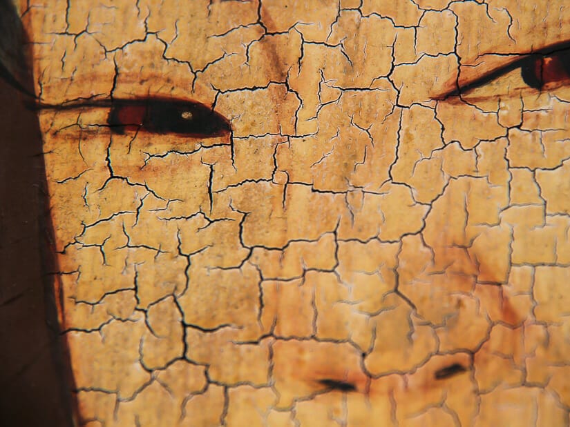 Close up of the eyes and nose of a painting of a woman that is covered in cracks