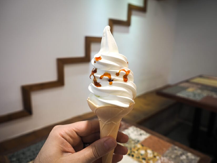 A hand holding up a soft serve ice cream cone inside Anping Treehouse Cafe