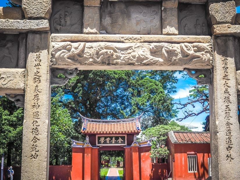 A stone gate with red entrance gate in background, which forms the entrance to the Confucius Temple in Tainan