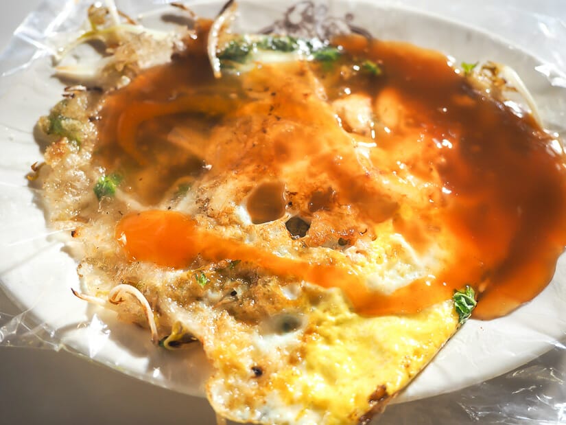 Close up of a crab meat oyster omelet with red sauce on it, taken at Garden Night Market