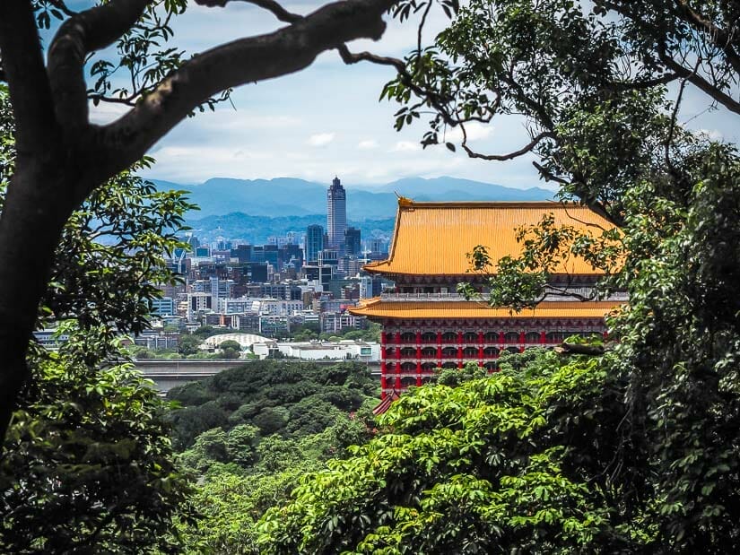 Red and orange Grand Hotel Taipei viewed between the trees on Jiantanshan hiking trail
