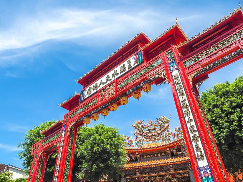 A tall red gate with a colorful temple behind it, Lady Linshui's Temple in Tainan