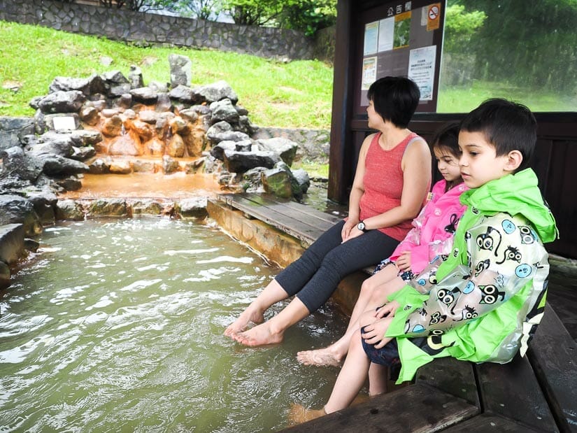 A mother and two children soaking their feet in hot water at Lengshuikeng after hiking in Yangmingshan