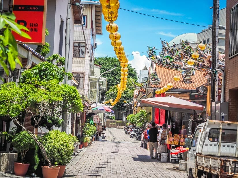 An alleyway leading to a temple, with a line of yellow lanterns running down the alley