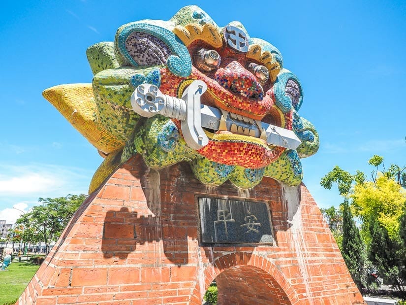 A colorful statue of a lion with a sword in its mouth with the Chinese characters for Anping on it