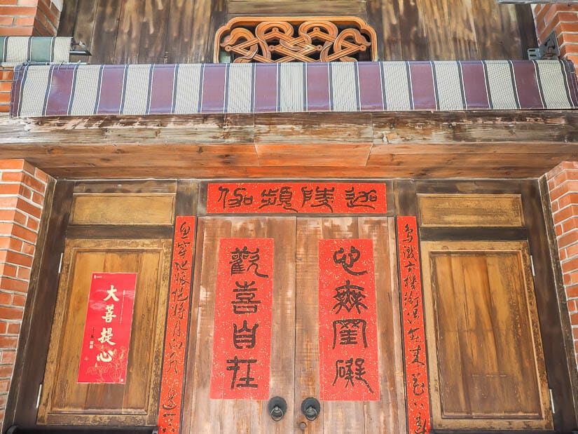 Wooden doors of an old neighborhood head residence in Anping with red Chinese couplet banners on them