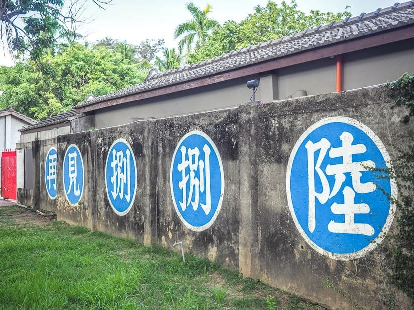 A cement wall at Farewell 886, a military dependents village in Zuoying, Kaohsiung, with some Mandarin characters in big blue circles painted on it.