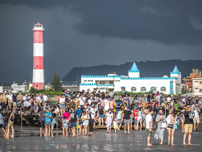 A crowded mass of people at the end of the Gaomei Wetlands dock, with a lighthouse in the background