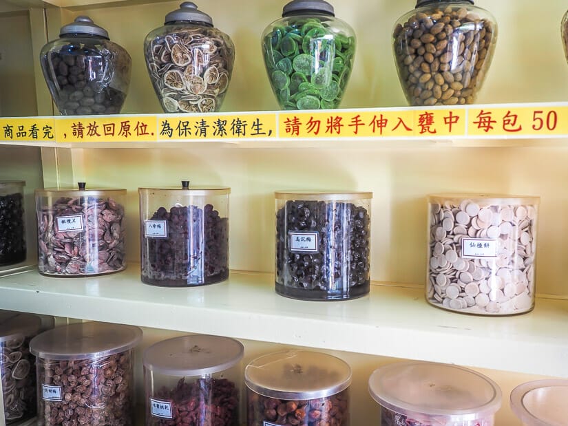 Some large glass jars full of dried fruits on a yellow shelf