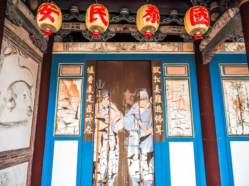 Cracked paintings on a wall and some lanterns hanging in Lugang Decang Temple