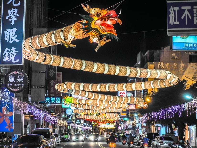 A street with a huge lantern display above it that looks like a long, winding dragon