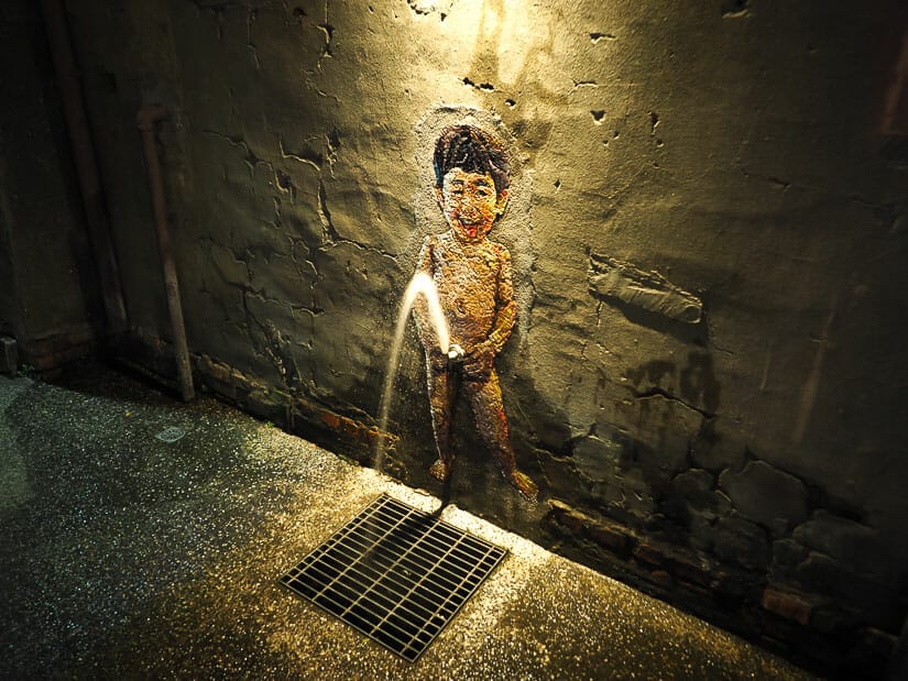 A painting of a boy on a wall in Pier 2 Art Center and it looks like he's peeing