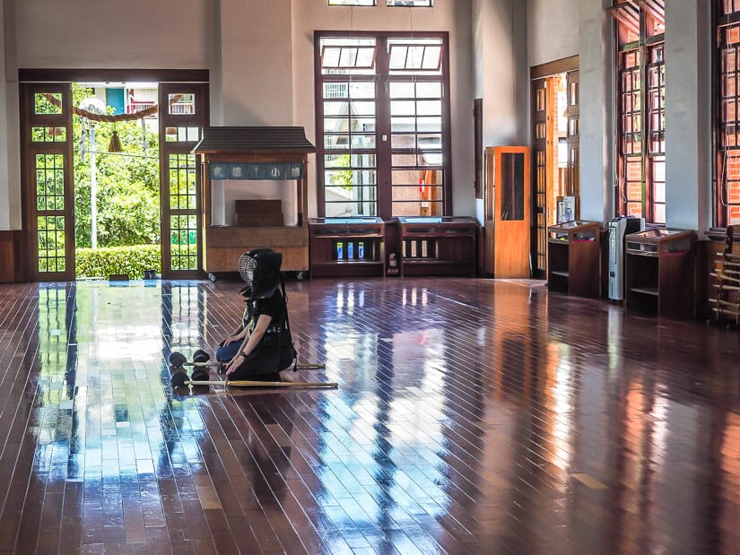 Two fighters kneeling on the wooden floor inside Wu De Martial Arts Center in Kaohsiung