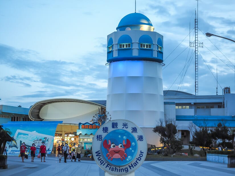 A blue and white lighthouse and tourist markets at Wuqi Harbor