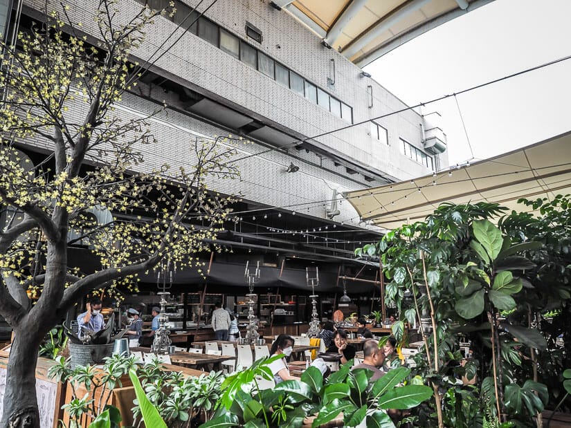 An outdoor patio with covering and some people dining on barbecued seafood at Addiction Aquatic Development