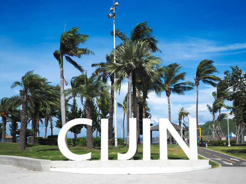 Statue of the words Cijin with palm trees around it