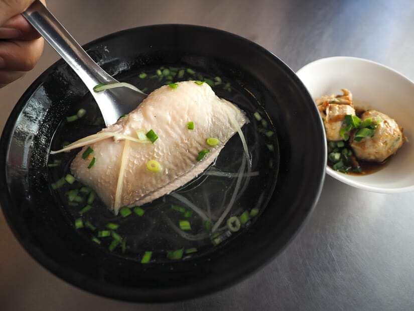A bowl of milkfish soup, with a hand holding up the fish piece in a spoon, from a seafood stall on Cijin Island